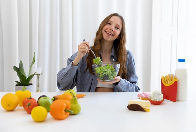 Mulher de tiro médio segurando uma tigela de salada