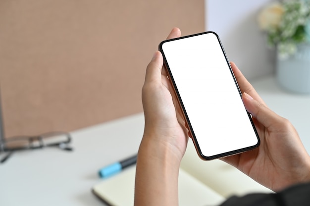 Mulher de tiro recortada usando smartphone maquete na mesa de escritório