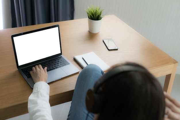 Mulher de tiro superior trabalhando na cadeira reclinável com o computador laptop laptop em casa.