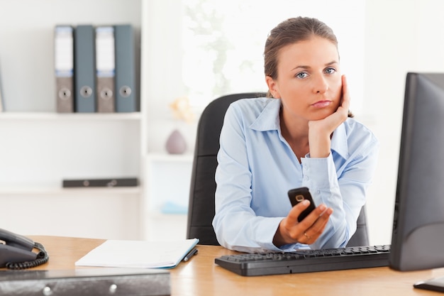 Mulher de trabalho pensativo usando um telefone celular