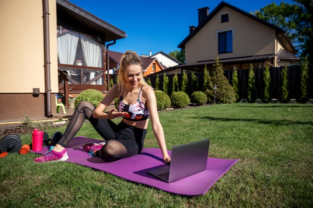 Mulher de treinador de fitness muito esportivo usando laptop durante o treinamento em vídeo on-line