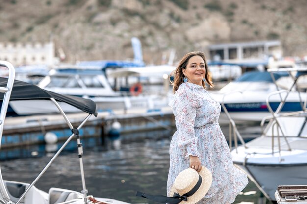 Mulher de turista caminha no cais de atracação de madeira com iates turísticos