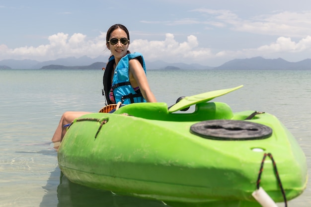 Mulher de turista sentada no caiaque lookign na bela praia tropical de férias.