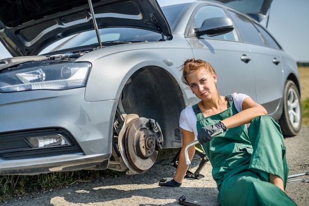 Mulher de uniforme trabalhando para manutenção do freio do carro. Reparo de carro. Trabalho de segurança