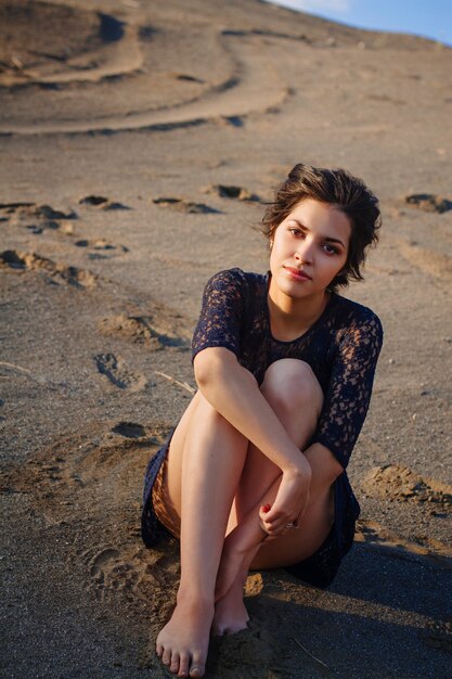 Mulher de vestido azul sentada na praia