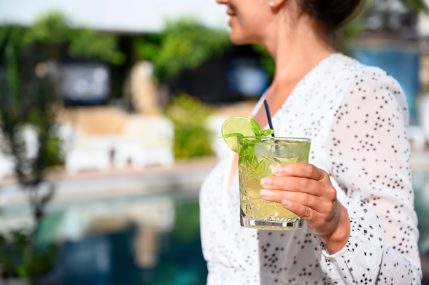 Foto mulher de vestido branco bebendo um coquetel de mojito