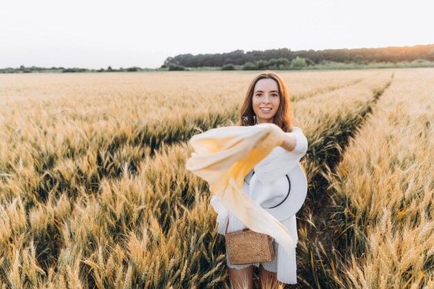 mulher de vestido branco e chapéu branco em um campo de trigo