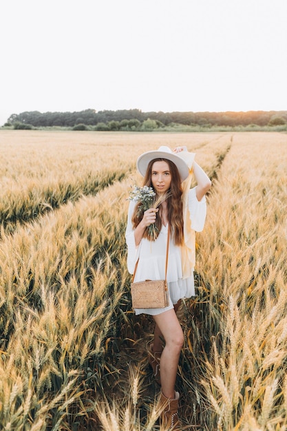 mulher de vestido branco e chapéu branco em um campo de trigo