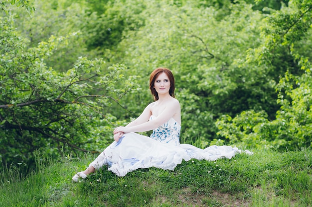 Mulher de vestido branco longo no jardim de verão