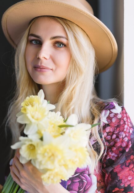 Mulher de vestido com um buquê de narcisos nas mãos