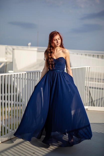 Mulher de vestido de pé na varanda contra o céu