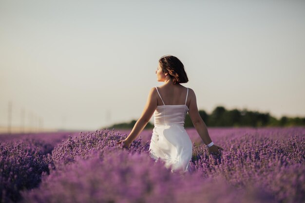 mulher de vestido de verão tocando flores roxas