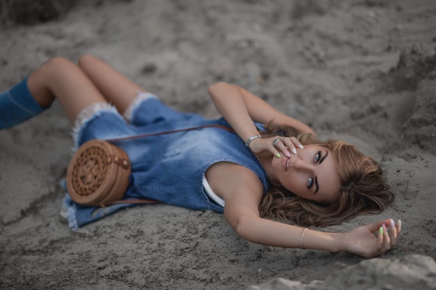 mulher de vestido jeans deitada na areia