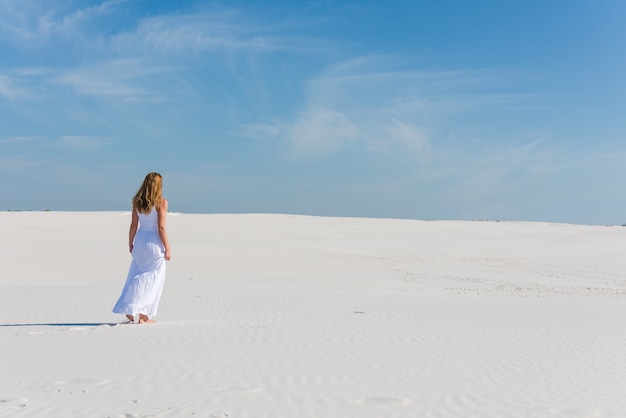 Mulher de vestido longo branco caminhar no deserto