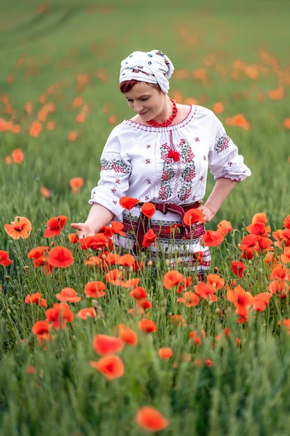 Foto mulher de vestido nacional ucraniano em um campo de papoulas floridas