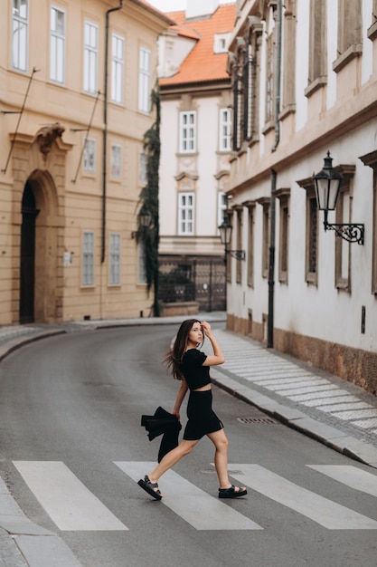 Mulher de vestido preto andando na cidade velha de Praga