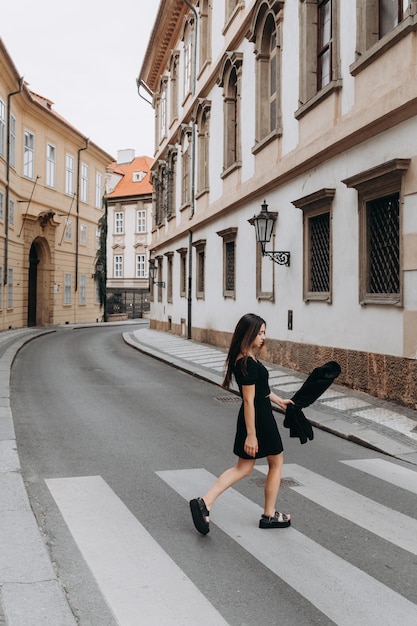 Mulher de vestido preto andando na cidade velha de Praga