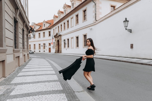 Mulher de vestido preto andando na cidade velha de Praga