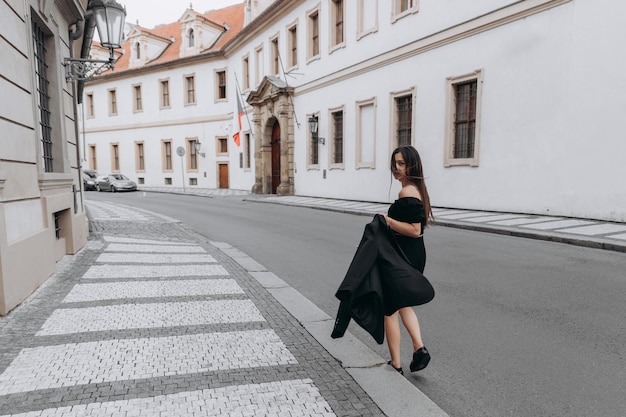 Mulher de vestido preto andando na cidade velha de Praga