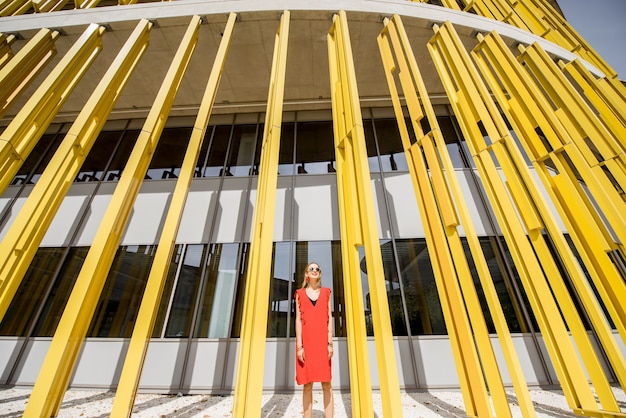 Mulher de vestido vermelho no fundo da parede do edifício amarelo moderno. Composição geométrica abstrata