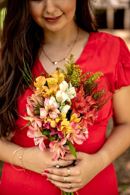 Mulher de vestido vermelho segurando um buquê de flores