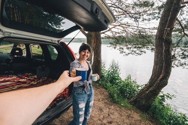 Mulher de viagem de carro de casal dando café para homem ponto de vista em primeira pessoa