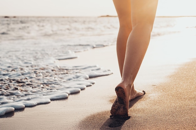 Mulher de viagem de praia andando na praia de areia deixando pegadas na areia Detalhe de pés femininos e areia dourada na praia de TenerifexA