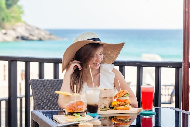 Mulher de viagens com hambúrgueres de fastfood, café e bebidas à base de suco em um café ao ar livre