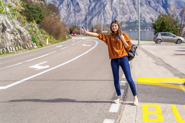 Mulher de viagens pedindo carona. Bela jovem Mochileiro feminina na estrada durante a viagem de férias nas montanhas Montenegro