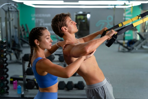 Foto mulher de vista lateral ajudando o homem a se exercitar na academia