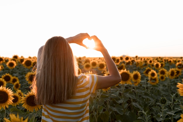 Foto mulher de vista traseira posando ao pôr do sol