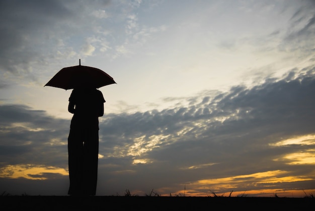 Mulher de youn silhueta com tão triste por do sol.
