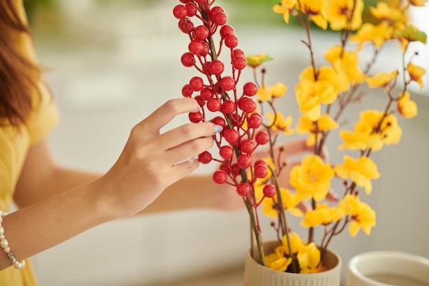 Mulher decorando a casa com galhos com flores e bagas