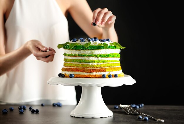 Foto mulher decorando bolo delicioso em fundo escuro