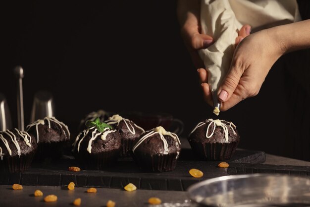 Foto mulher decorando cupcake saboroso com cobertura na mesa