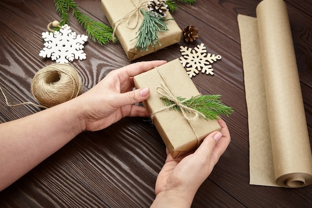 Mulher decorando presentes de Natal na mesa de madeira