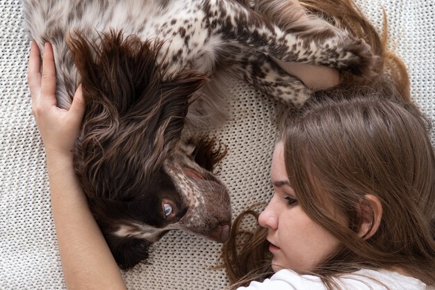 Mulher deitada com os olhos de cores diferentes do russo spaniel cão chocolate merle. no sofá. Conceito de cuidados de animais de estimação.