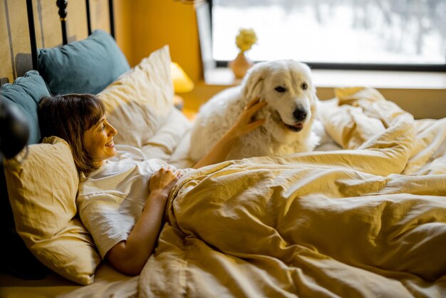 Mulher deitada com seu cachorro enorme e fofo na cama