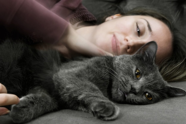 Mulher deitada na cama com gato preto britânico