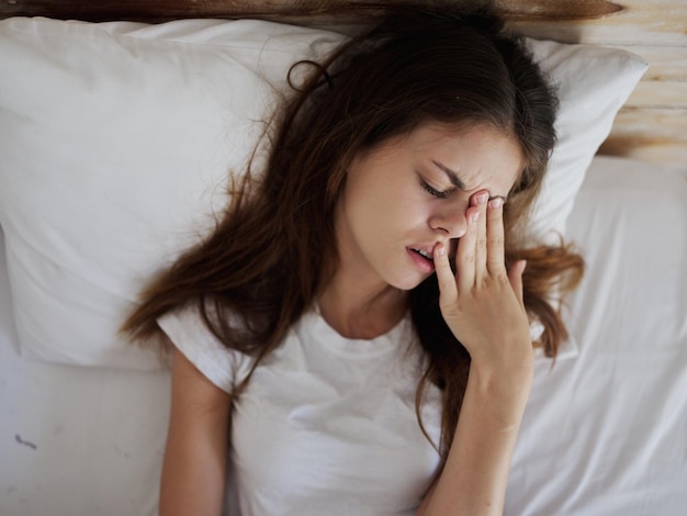 Mulher deitada na cama com olhos fechados expressão facial descontente