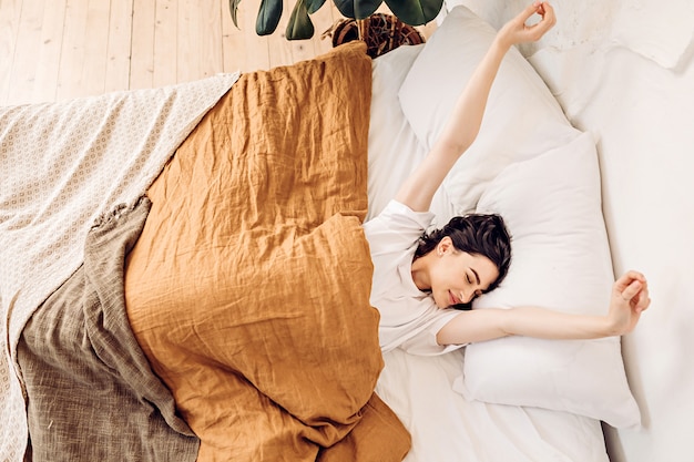 Mulher deitada na cama, debaixo dos cobertores