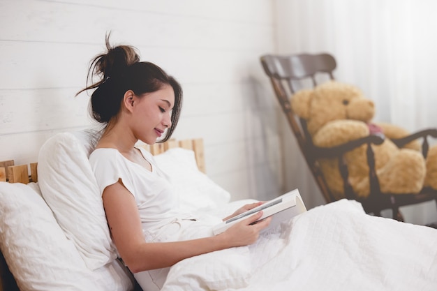 Mulher deitada na cama lendo um livro