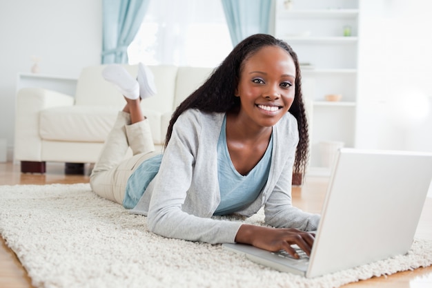 Mulher deitada no chão com o laptop