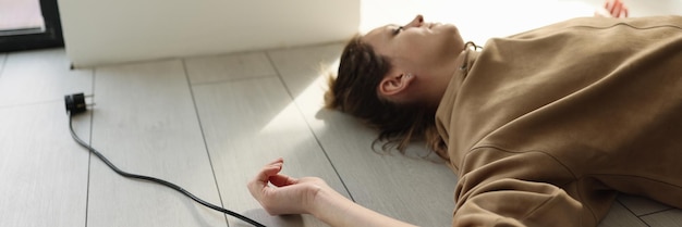 Mulher deitada no chão com os olhos fechados perto de cabo elétrico com conceito de plugue perigoso