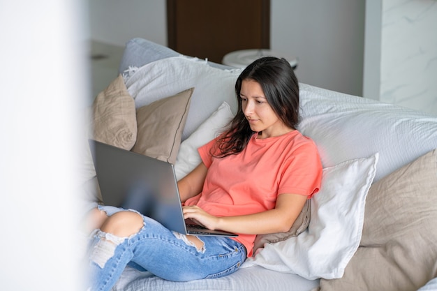 Mulher deitada no sofá com um laptop