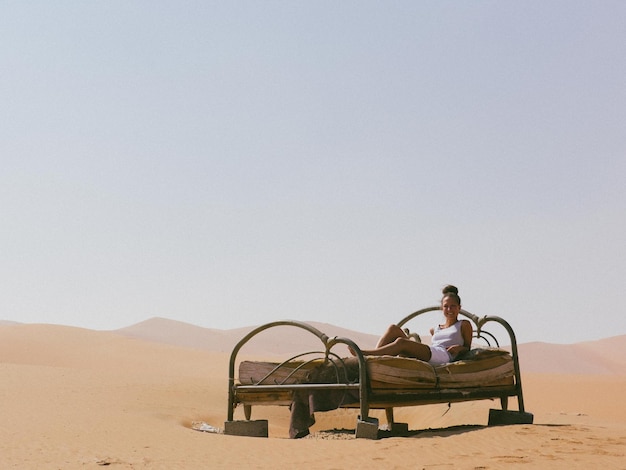 Mulher deitada numa cama velha no deserto