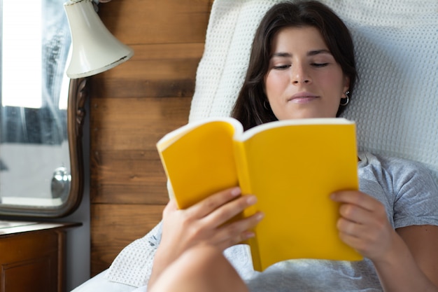 Mulher, deitando, cama, e, livro leitura