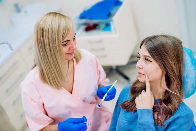 Mulher dentista em luvas cor de rosa. Trabalhando com o paciente. Paciente do sexo feminino com dor de dente. Conceito de higiene bucal