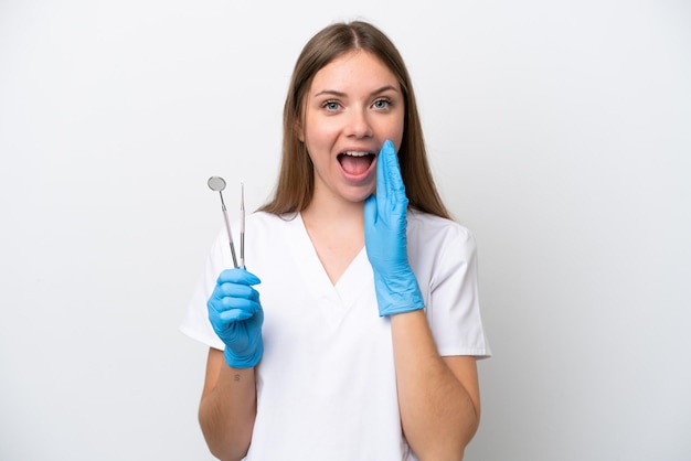 Mulher dentista segurando ferramentas isoladas no fundo branco com surpresa e expressão facial chocada