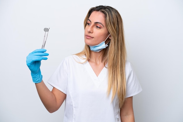 Mulher dentista segurando ferramentas isoladas no fundo branco, olhando para o lado